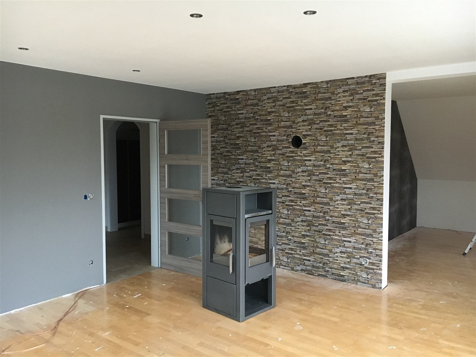 Wohnzimmer mit Steinwand in Naturoptik und Kaminofen