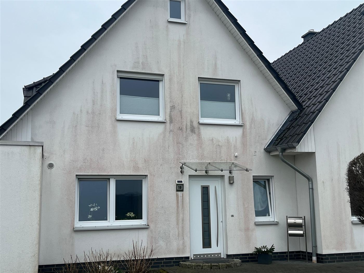 Fleckige, verschmutzte Hausfassade vor der Reinigung und dem Anstrich